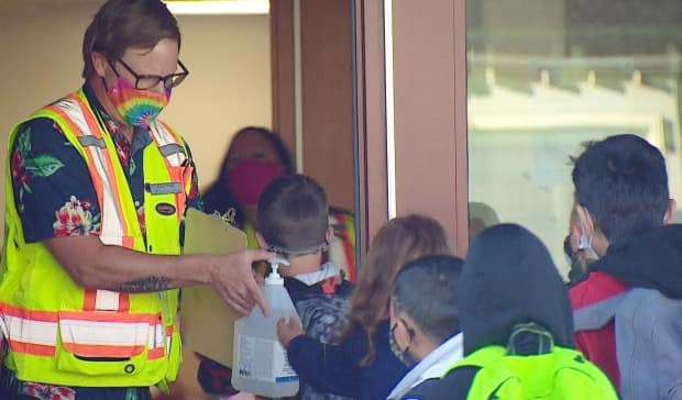 Students line up to have their hands sanitized at a northwest Calgary school on the first day back in September 2020. (Mike Symington/CBC - image credit)