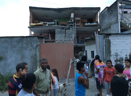 People stand outsdie a destroyed house after a 5.8-magnitude earthquake shook Ecuador's Pacific coast early on Monday, in Atacames, Ecuador, December 19, 2016. REUTERS/Ricardo Landeta