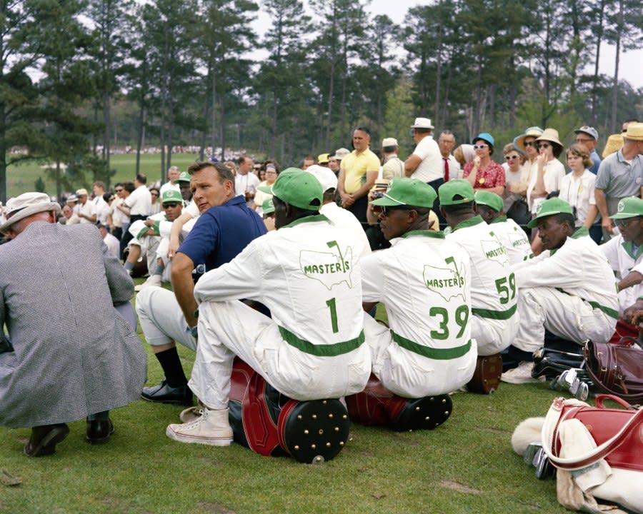 AUGUSTA, GA – APRIL 1965: Arnold Palmer looks over his shoulder as he sits with a group of caddies during the 1965 Masters Tournament at Augusta National Golf Club on April 8-11, 1965 in Augusta, Georgia. (Photo by Augusta National/Getty Images)