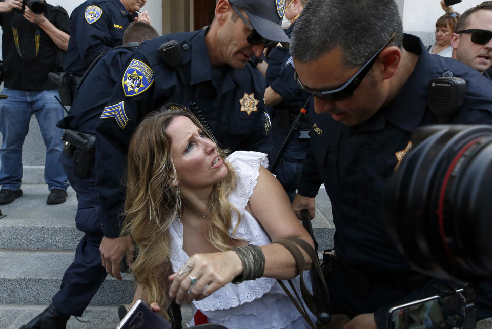 Tara Thornton is detained by California Highway Patrol officers during a demonstration against Gov. Gavin Newsom's stay-at-home orders aimed at slowing the spread of the new coronavirus, at the Capitol in Sacramento, Calif., Friday, May 1, 2020. Several people were taken into custody during the protest calling for Newsom to end the restrictions and allow people return to work. (AP Photo/Rich Pedroncelli)