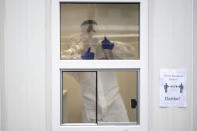 An employee shows thumbs-up inside a container at the test center for the coronavirus at Central Station in Cologne, Germany, Friday, Oct. 23, 2020. According to the Robert Koch Institute, Germany's federal government agency and research institute responsible for disease control and prevention, the number of new infections with the corona virus in Cologne has risen to 120.1 per 100,000 inhabitants. (Marius Becker/dpa via AP)