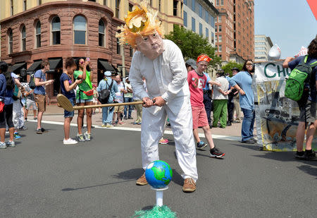 A protester in a costume depicting Trump sets an Earth on a tee as he holds a golf club while joining demonstrators moving down Pennsylvania Avenue during a People's Climate March, to protest U.S. President Donald Trump's stance on the environment, in Washington, U.S., April 29, 2017. REUTERS/Mike Theiler