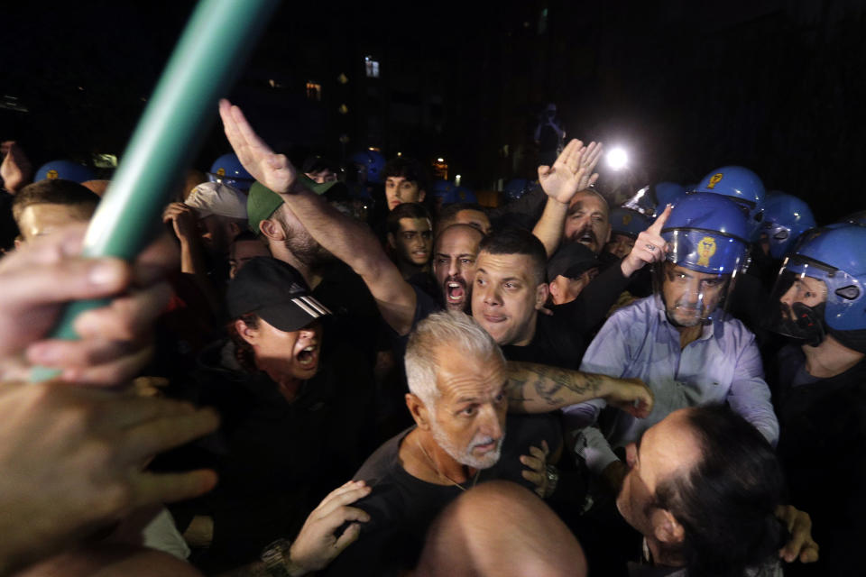 FILE - In this Sept. 8, 2017 file photo, demonstrators from Far-Right groups, Forza Nuova and Roma ai Romani (New Force and Rome to Romans) confront with Italian Policemen in riot gears near a migrants and refugees shelter during a protest against their presence in Rome. Fascist salutes -- long a public taboo -- have made their way out of the hooligan sections of soccer stadiums and into city streets, as demonstrated by a couple of dozen of the Roman football squad Lazio’s historically right-wing and fascist ‘’ultra’’ fans on visitors’ turf in Milan. Fringe far-right political parties are emboldened to shout fascist slogans and raise one-armed fascist salutes in protests against placing Roma families -- a minority persecuted in World War II -- in public housing in the capital Rome. (AP Photo/Gregorio Borgia, file)