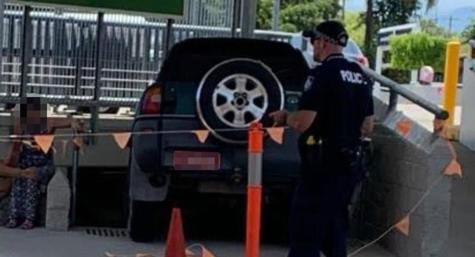 A police officer stands behind a 4WD driven down a stairwell at a shopping centre.