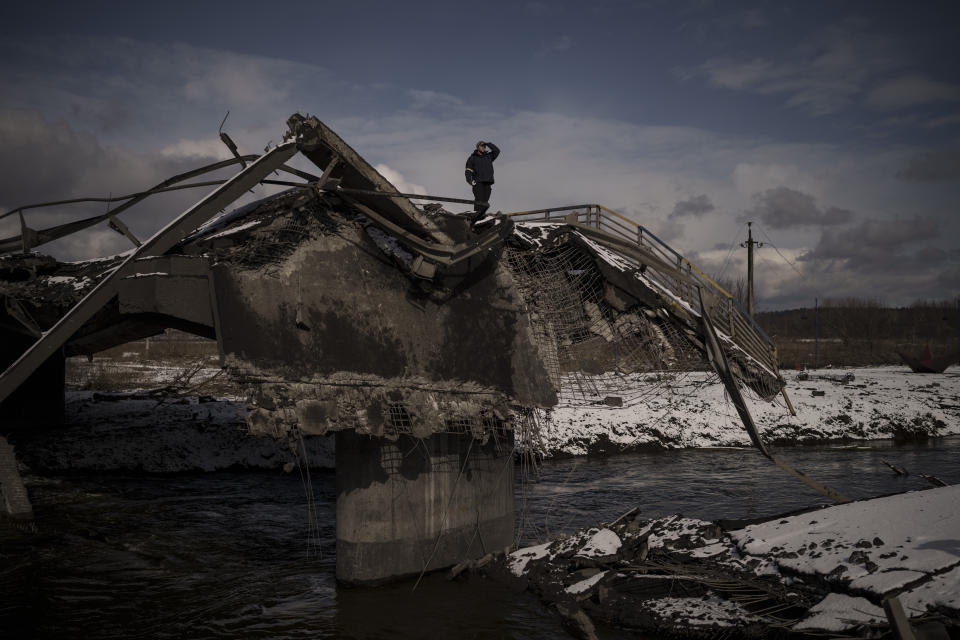 FILE - A man stands atop a destroyed bridge in Irpin, on the outskirts of Kyiv, Ukraine, Tuesday, March 8, 2022. Quantifying the toll of Russia’s war in Ukraine remains an elusive goal a year into the conflict. Estimates of the casualties, refugees and economic fallout from the war produce an complete picture of the deaths and suffering. Precise figures may never emerge for some of the categories international organizations are attempting to track. (AP Photo/Felipe Dana, File)