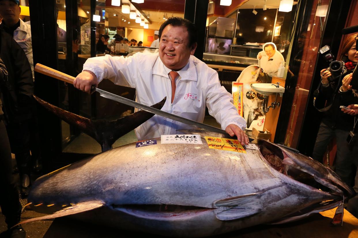 Kiyoshi kimura, president of Kiyomura K.K, poses for photos with a 180.4 kilograms (397 pounds) fresh tuna after this year's first auction at Tsukiji Market 