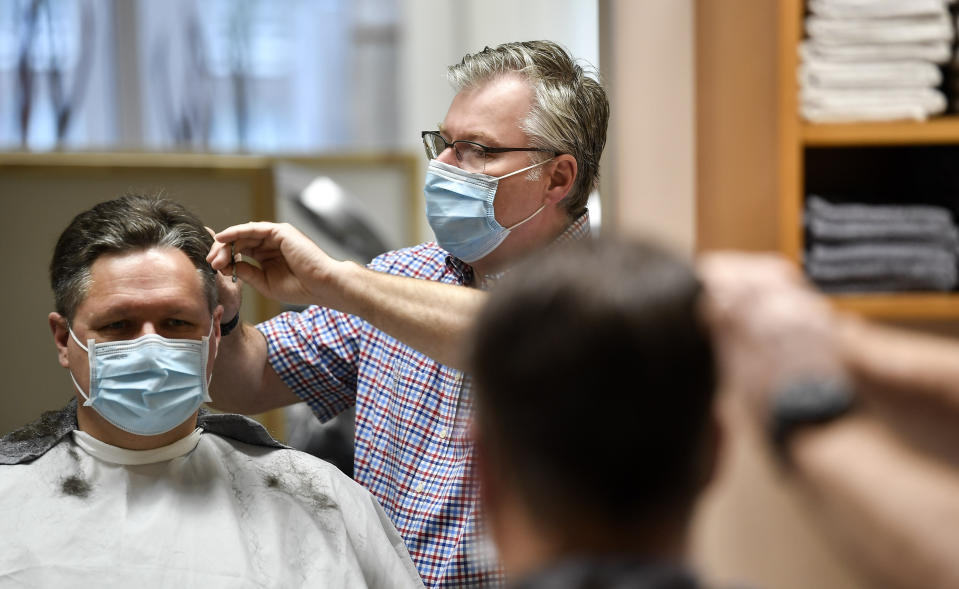 Hairdresser Holger Augustin cuts hair of a customer at his barber shop in Gelsenkirchen, Germany, Monday, March 1, 2021. Hairdressers across Germany have reopened for business this morning after a more than 2-month closure, another cautious step as the country balances a desire to loosen restrictions with concern about the impact of more contagious coronavirus variants. (AP Photo/Martin Meissner)