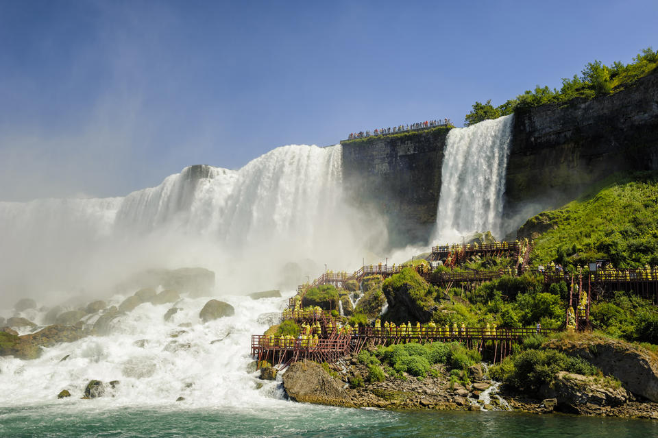 <p>Tourists take the Cave of the Winds tour near the base of the American Falls, one of the three falls that make up Niagara Falls in N.Y. (Photo: Vincent Boisvert/Moment RF/Getty Images) </p>