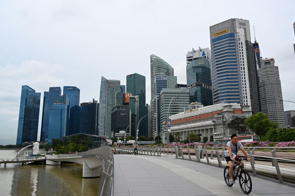 A man cycles along a bridge in Singapore on January 4, 2021, as the skyline is seen in the background. (Photo by Roslan RAHMAN / AFP) (Photo by ROSLAN RAHMAN/Afp/AFP via Getty Images)