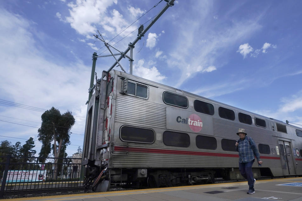 A person walks past a train at a Caltrain station in Burlingame, Calif., Monday, June 5, 2023. California's public transit agencies say they are running out of money, plagued by depleted ridership from the pandemic and soon-to-expire federal aid. But California's state government is having its own financial problems, leaving the fate of public transit agencies uncertain in this car-obsessed state. (AP Photo/Jeff Chiu)