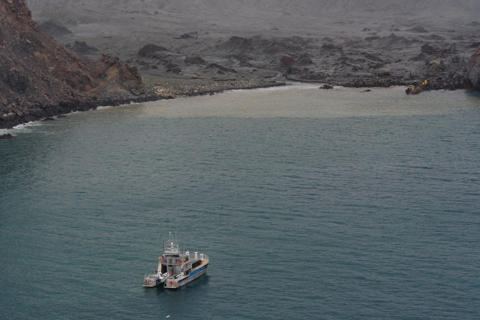 A New Zealand Defence boat approaches White Island which is covered in ash.