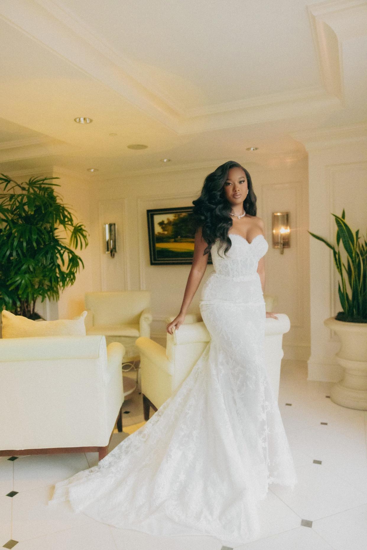 A bride poses on a chair in her wedding dress.