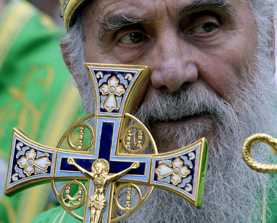 FILE - In this May 24, 2012, file photo, Serbian Orthodox Church Patriarch Irinej holds a cross during a procession marking Belgrade's patrons saint day, Spasovdan, in downtown Belgrade. Serbia's Orthodox Church said Friday, Nov. 20, 2020, the leader, Patriarch Irinej, has died after testing positive for the coronavirus. He was 90. (AP Photo/Darko Vojinovic, File)