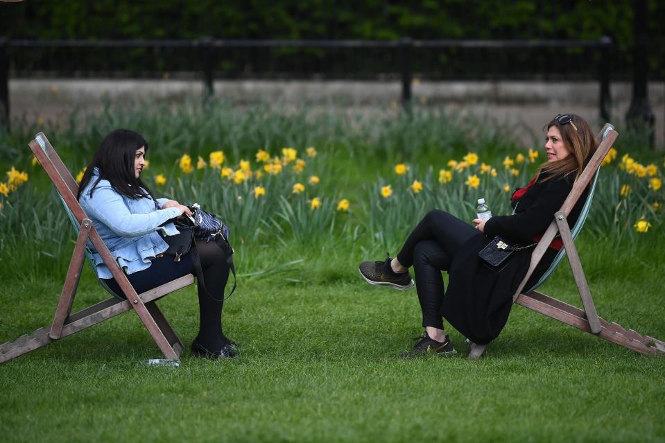 Two women sitting in deck chairs in Green Park, London, after Covid rules were relaxed this weekPA