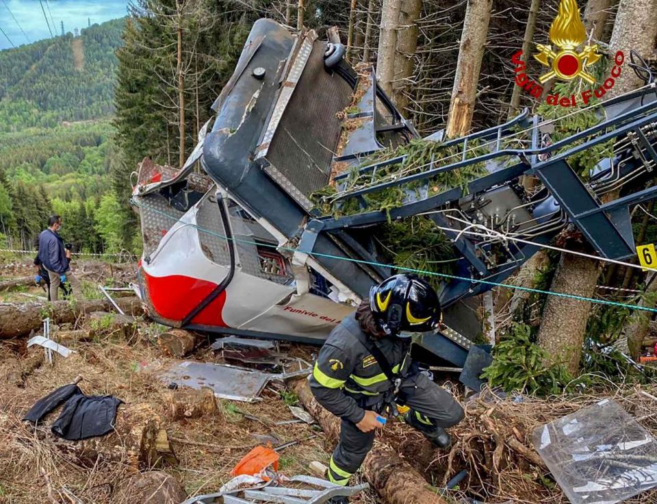 Rescuers work by the wreckage of a cable car after it collapsed near the summit of the Stresa-Mottarone line in the Piedmont region, northern Italy, Sunday, May 23, 2021. A cable car taking visitors to a mountaintop view of some of northern Italy's most picturesque lakes plummeted to the ground Sunday and then tumbled down the slope, killing at least 13 people and sending two children to the hospital, authorities said. (Italian Vigili del Fuoco Firefighters via AP)