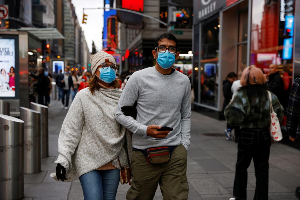 People wearing protective face masks, amid the coronavirus pandemic, walk through Times Square in New York City, November 22, 2021. REUTERS/Shannon Stapleton