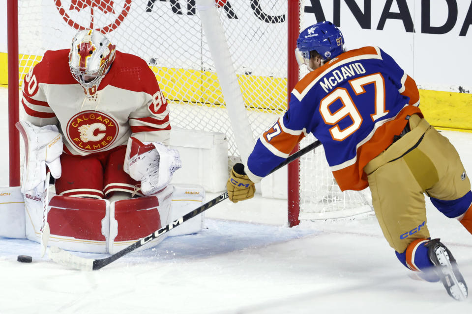 Edmonton Oilers' Connor McDavid, right, has a shot stopped by Calgary Flames goalie Dan Vladar during the first period of an NHL hockey game Saturday, Jan. 20, 2024, in Calgary, Alberta. (Larry MacDougal/The Canadian Press via AP)