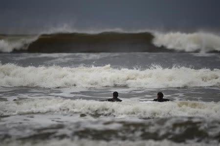 Surfers watch as waves approach in the Atlantic on the eve of storm Ophelia in an area where the tide should be out in the County Clare town of Lahinch, Ireland October 15, 2017. REUTERS/Clodagh Kilcoyne