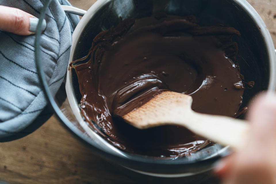 A wooden spoon mixes molten chocolate. (getty)