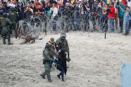 U.S. Customs and Border Protection (CBP) officials detain people during a gathering in support of the migrant caravan in San Diego, U.S., close to the border wall between the United States and Mexico, as seen from Tijuana, Mexico December 10, 2018. REUTERS/Carlos Garcia Rawlins