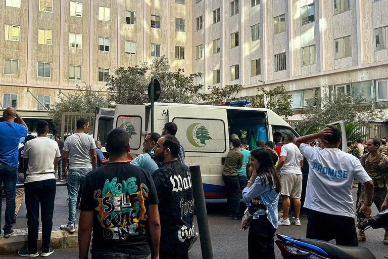 Varias personas reaccionan cerca de una ambulancia mientras trasladan a los heridos a un hospital de Beirut el 17 de septiembre de 2024, tras las explosiones registradas en varios bastiones de Hezbollah en Líbano, en medio de las tensiones transfronterizas entre Israel y los combatientes de Hezbollah.