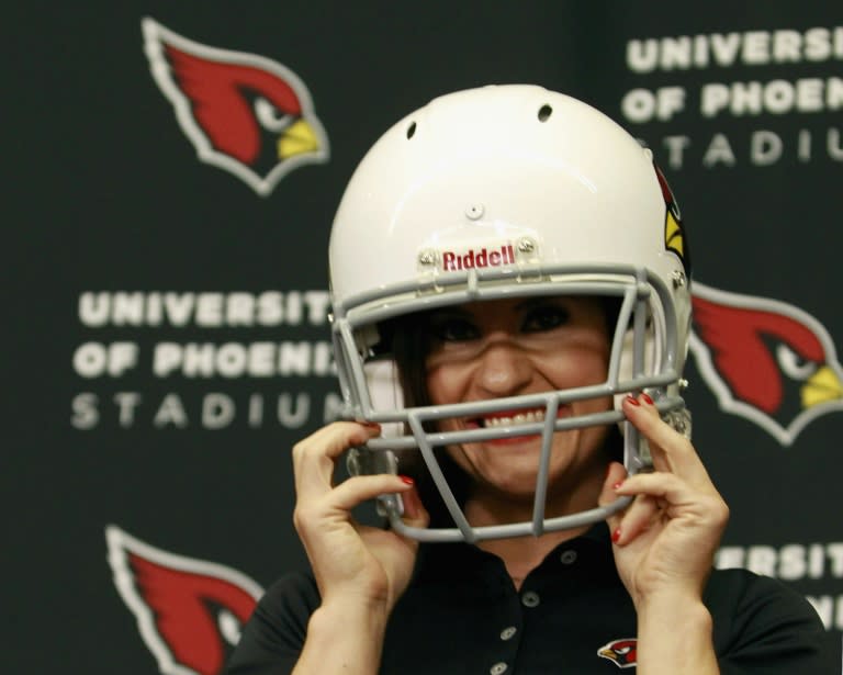 Jen Welter puts on a Arizona Cardinals helmet after being named an intern coach to the team during a press conference on July 28, 2015 in Tempe, Arizona