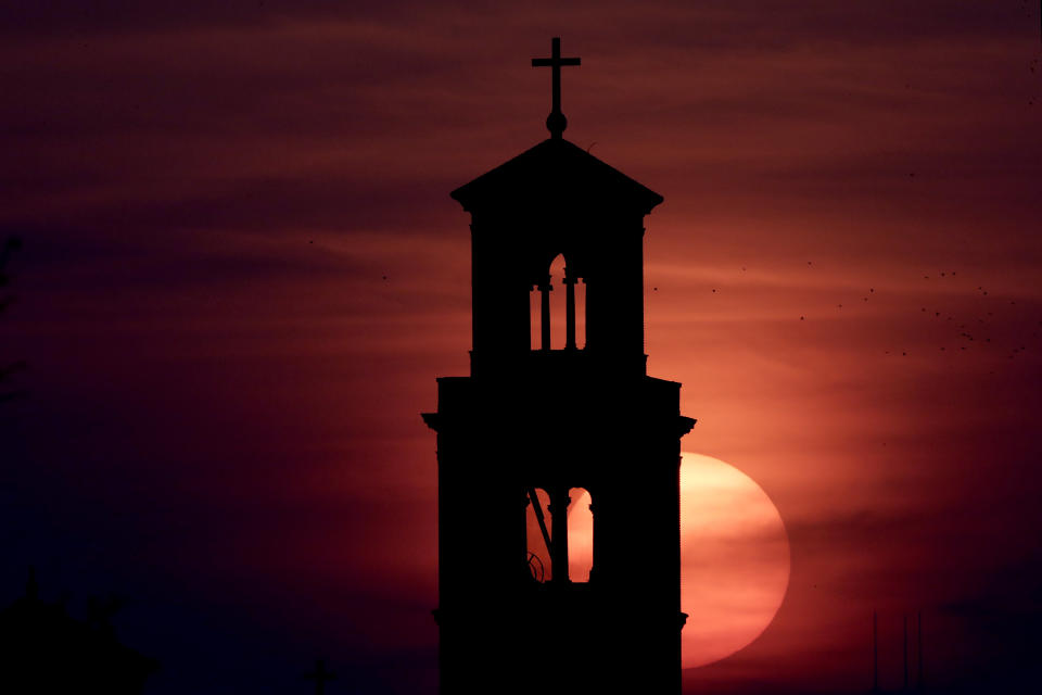 Our Lady of Sorrows Catholic Church is silhouetted against the rising sun in Kansas City, Mo., Wednesday, April 8, 2020. With Easter Sunday in four days, many churches are looking for ways to celebrate the occasion in light of stay-at-home orders and restrictions on gathering in an effort to slow the spread of the new coronavirus. (AP Photo/Charlie Riedel)