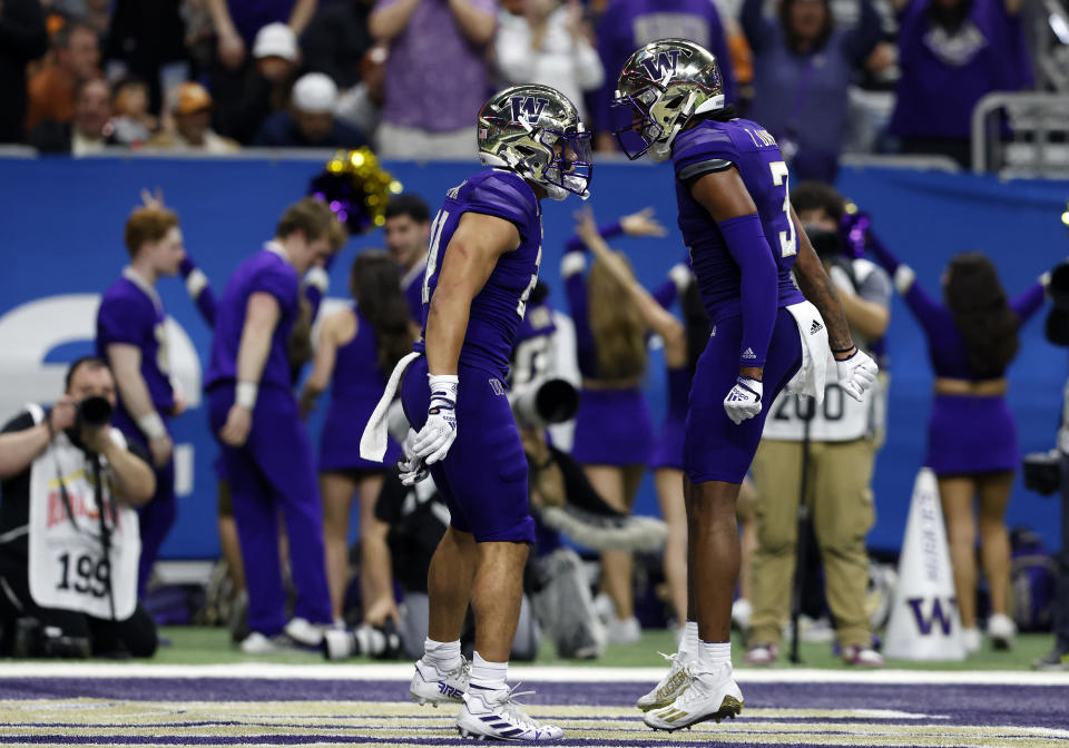 SAN ANTONIO, TEXAS - DECEMBER 29: Washington Huskies running back Wayne Taulapapa (21) and Washington Huskies wide receiver Taj Davis (3) play Valero Alamo Bowl football with Taulapapa at the Alamodome on December 29. San Antonio, Texas, 2022, after scoring a touchdown against the Texas Longhorns during a game in 2022.  (Photo by Adam Davis/Icon Sportswire via Getty Images)