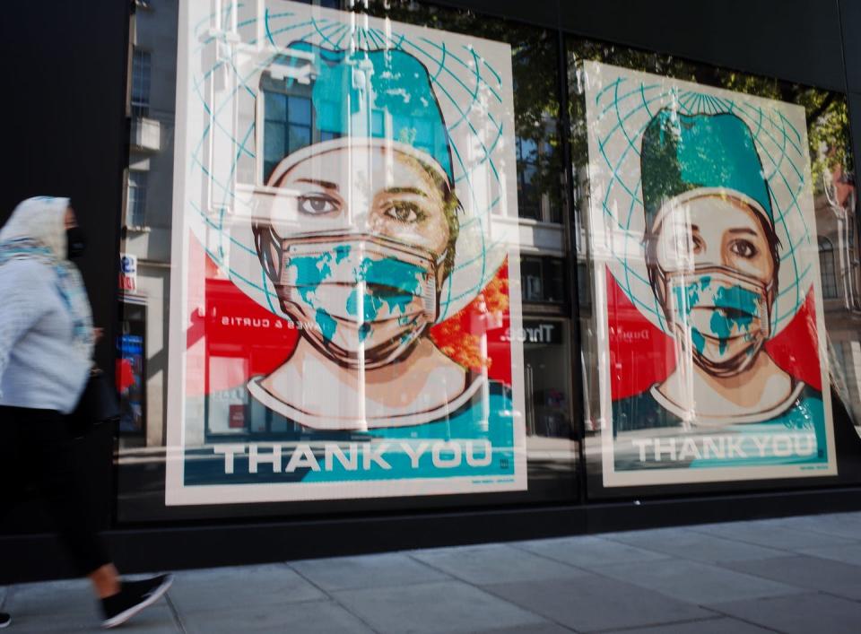 <span class="caption">Wishing won't be enough to make the pandemic history.</span> <span class="attribution"><a class="link " href="https://www.gettyimages.com/detail/news-photo/woman-wearing-a-face-mask-walks-past-digital-displays-news-photo/1212048671" rel="nofollow noopener" target="_blank" data-ylk="slk:David Cliff/NurPhoto via Getty Images;elm:context_link;itc:0;sec:content-canvas">David Cliff/NurPhoto via Getty Images</a></span>