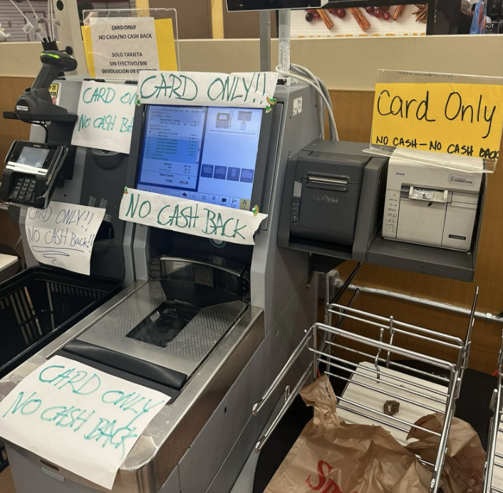 A self-checkout machine with multiple signs stating 