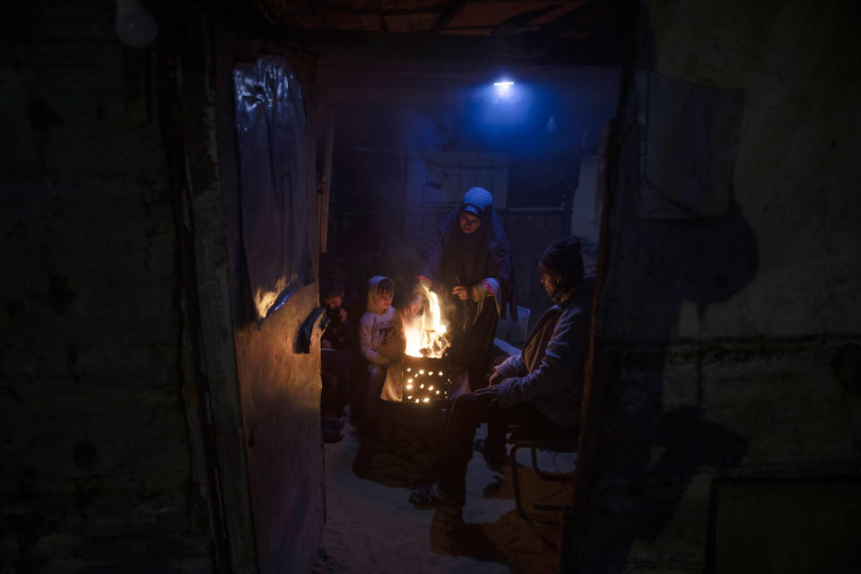 A Palestinian family warm themselves by a fire during a cold weather spell in a slum on the outskirts of the Khan Younis refugee camp, southern Gaza Strip, Wednesday, Jan. 19, 2022. (AP Photo/Khalil Hamra)