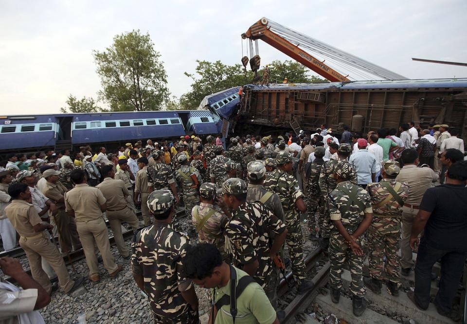 Security personnel and rescue members stand next to damaged coaches of a passenger train after a collision in Khalilabad in the northern Indian state of Uttar Pradesh May 26, 2014. (REUTERS/Stringer)