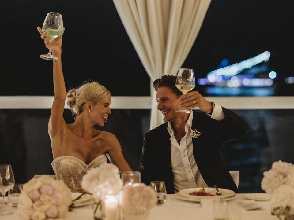 A bride and groom raise their glasses in a toast at their wedding.