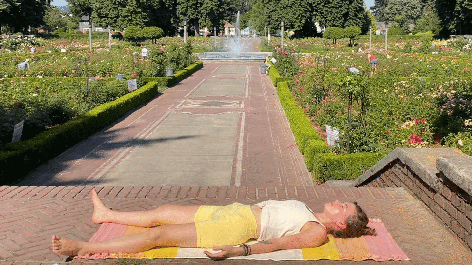 Woman lying on a yoga rug resting in Savasana