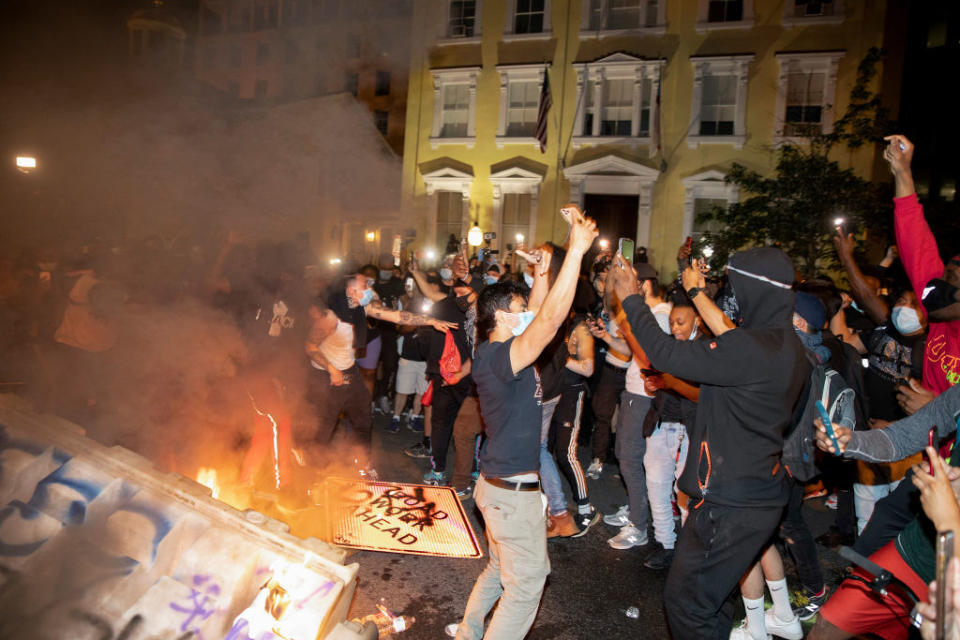 Demonstrators are seen chanting in front of a fire and graffitied signs in Washington, DC. Source: Getty Images