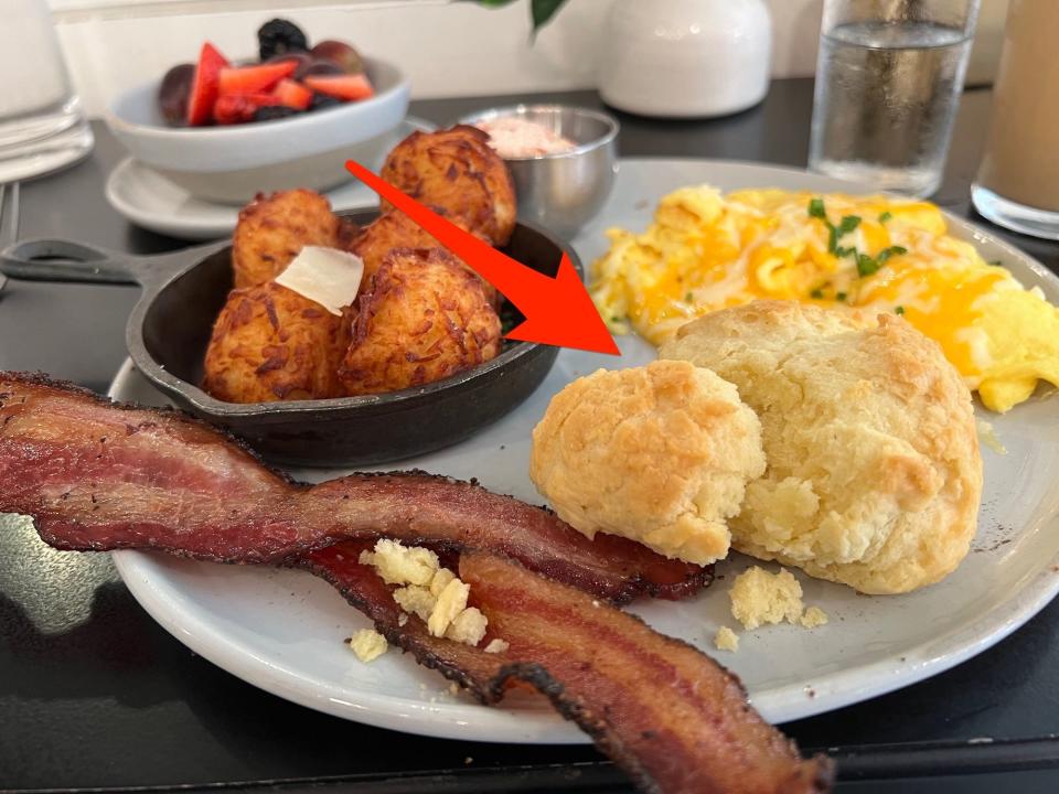 A plate of breakfast food with an arrow pointing at a biscuit.