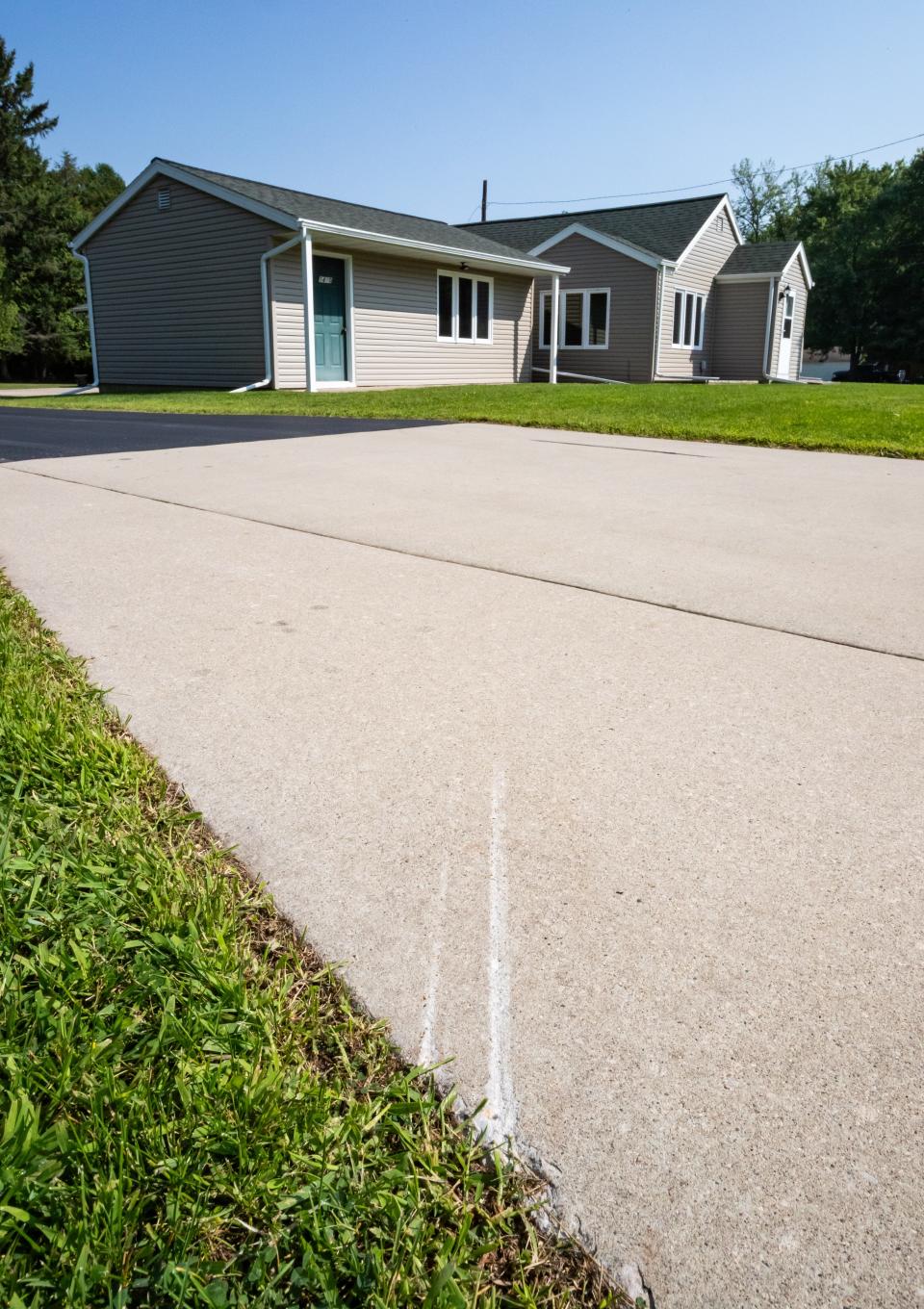 A mark on pavement shows where a car jumped the curb and crashed into Cornelius Vannieuwenhoven's house in Suamico, Wis., pictured on Friday, August 18, 2023.