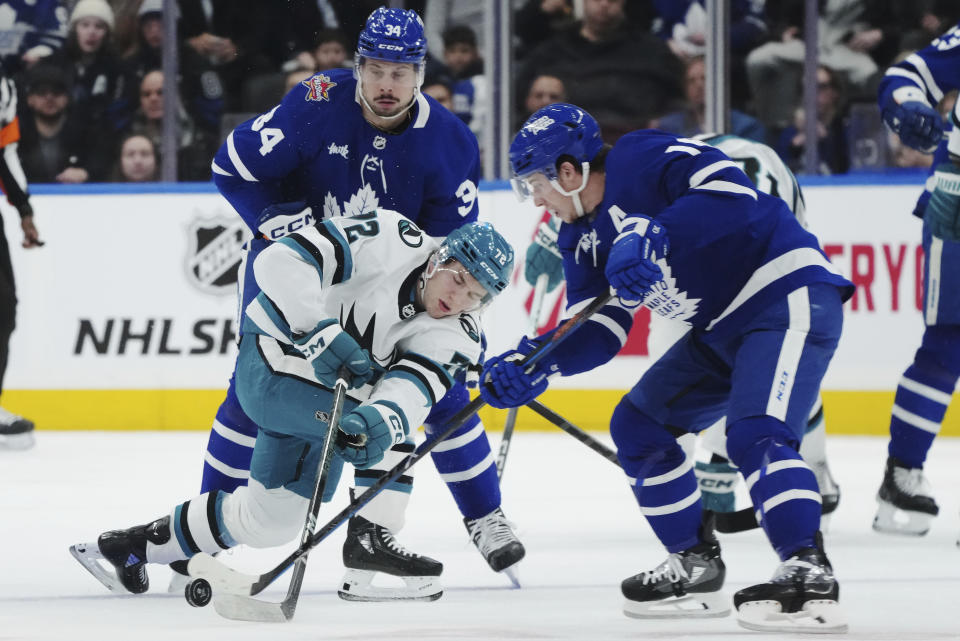 Toronto Maple Leafs forward Auston Matthews (34) and forward Mitchell Marner (16) battle for the puck with San Jose Sharks forward William Eklund (72) during the first period of an NHL hockey game, Tuesday, Jan. 9, 2024 in Toronto. (Nathan Denette/The Canadian Press via AP)