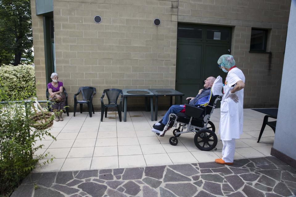 Fermo Signorelli, 71, sits in a wheelchair at a safe distance to see his wife Mariuccia Rizzi at the Martino Zanchi Foundation nursing home in Alzano Lombardo, Italy, Friday, May 29, 2020. (AP Photo/Luca Bruno)