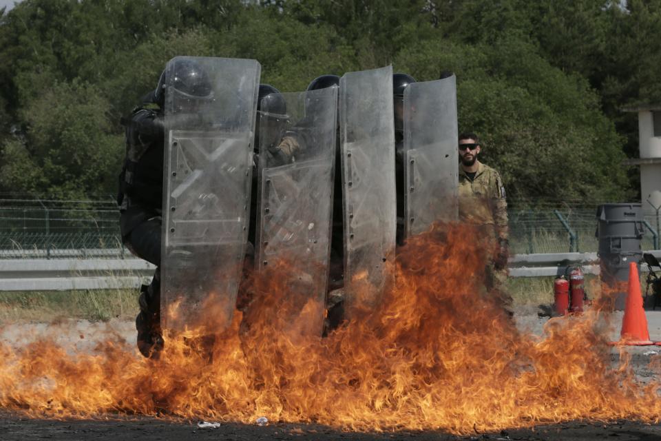 A photo of soldiers from the Italian Army practicing defending themselves against thrown incendiary devices with riot shields.