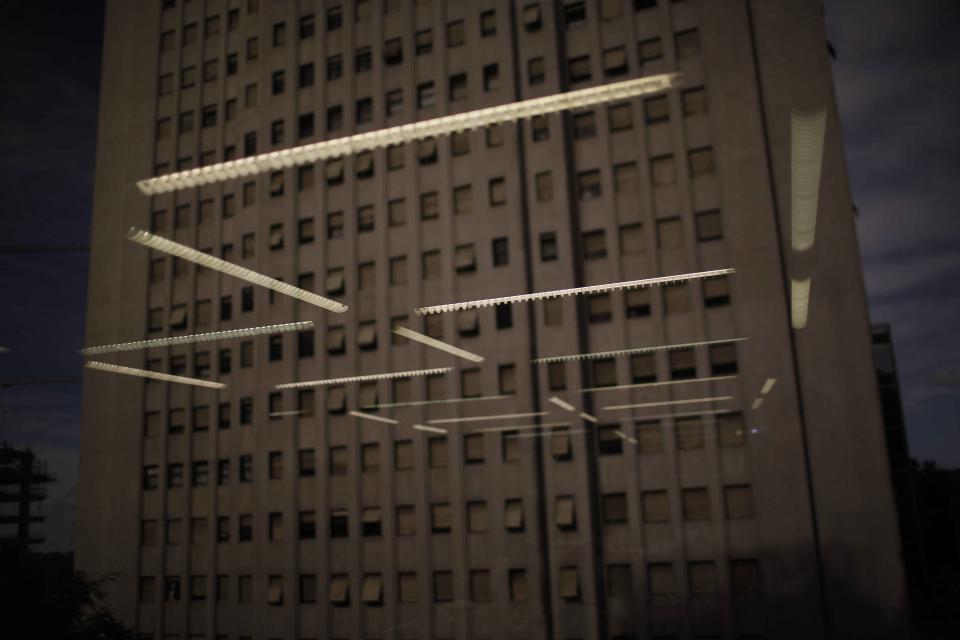 In this Feb. 14, 2014 photo, office light are reflected in a high rise office window in Buenos Aires, Argentina. Argentines have suffered through a tough summer, with tropical rain that provided no relief from the heat and humidity, people having to throw out rotten food because of rolling power blackouts and soaring oil and gas prices, all amid rising inflation that is making it ever harder to reach the end of the month. The strain is evident on the faces of subway riders and others making their way home in Buenos Aires, where signs of poverty and decay are ubiquitous just beyond the glamorous streets where tourists go. (AP Photo/Rodrigo Abd)