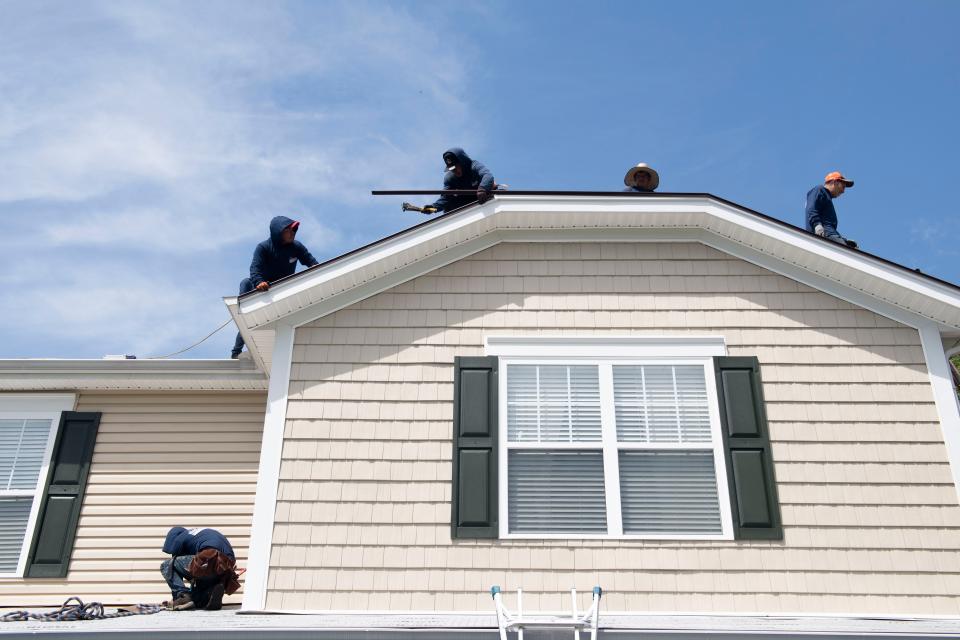 Workers install shingles on a roof at a home in  Hendersonville, Tenn., Thursday, April 20, 2023.