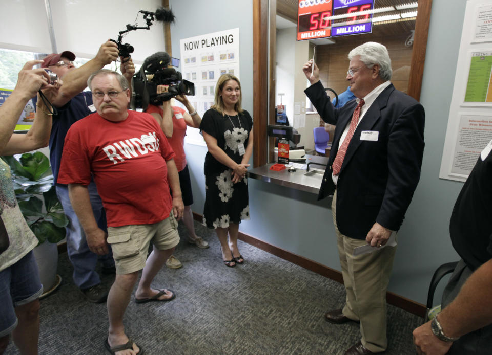 Attorney Joe Day, right, holds up the winning $241 million Powerball ticket before it is cashed in for his clients, a group of workers from the Quaker Oats plant in Cedar Rapids, Iowa, at the Iowa Lottery headquarters, Wednesday, June 20, 2012, in Des Moines, Iowa. Lottery spokeswoman Mary Neubauer says one of the workers bought the winning ticket for the group for the June 13 drawing and the winnings will be split 20 ways.(AP Photo/Charlie Neibergall)