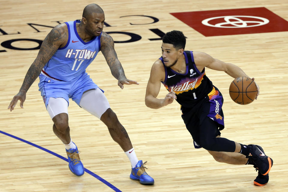 Phoenix Suns guard Devin Booker (1) drives around Houston Rockets forward P.J. Tucker (17) during the second half of an NBA basketball game Wednesday, Jan. 20, 2021, in Houston. (AP Photo/Michael Wyke)