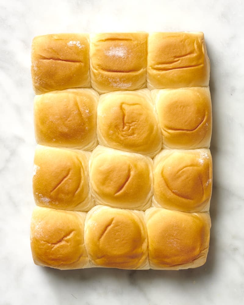 Overhead view of twelve hawaiin rolls on a marble surface.