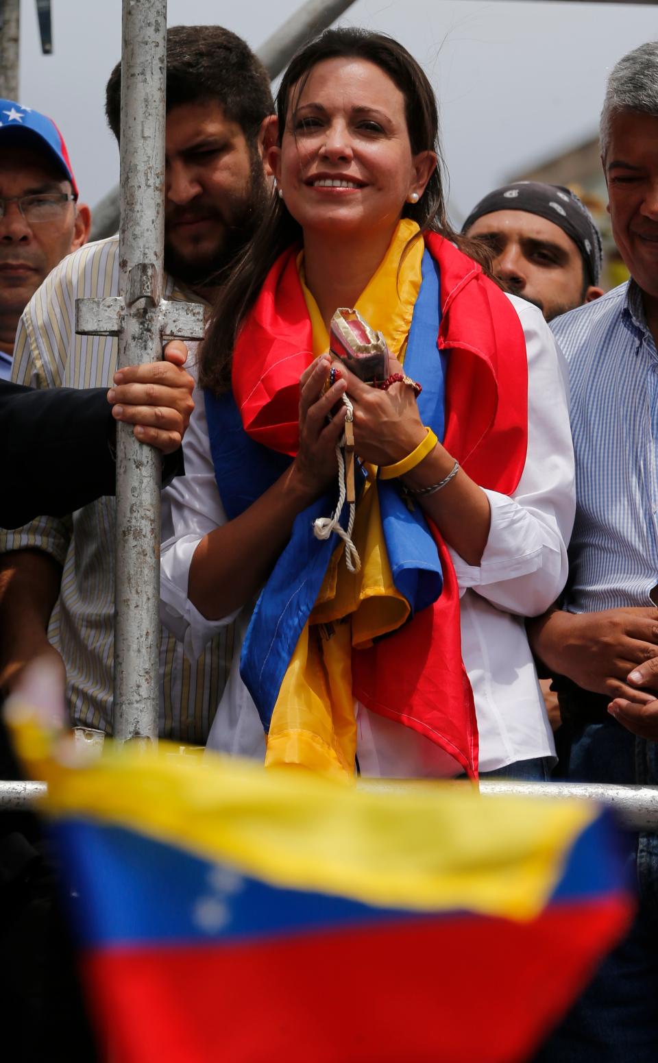 Maria Corina Machado, is surrounded by colleagues during a rally in Caracas, Venezuela, Tuesday, April 1, 2014. Protesters wearing white T-shirts and hats in the red, yellow and blue, of Venezuela's flag have gathered to cheer the opposition lawmaker who was stripped of her seat in congress by the government last week. This is Machado's first major public appearance since Venezuela's Supreme Court confirmed the stripping of Machado's parliamentary seat after she addressed the Organization of American States at the invitation of Panama. (AP Photo/Fernando Llano)