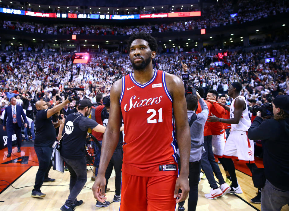 TORONTO, ON - MAY 12:  Joel Embiid #21 of the Philadelphia 76ers looks on as Kawhi Leonard #2 of the Toronto Raptors celebrates with teammates after sinking a buzzer beater to win Game Seven of the second round of the 2019 NBA Playoffs at Scotiabank Arena on May 12, 2019 in Toronto, Canada.  NOTE TO USER: User expressly acknowledges and agrees that, by downloading and or using this photograph, User is consenting to the terms and conditions of the Getty Images License Agreement.  (Photo by Vaughn Ridley/Getty Images)