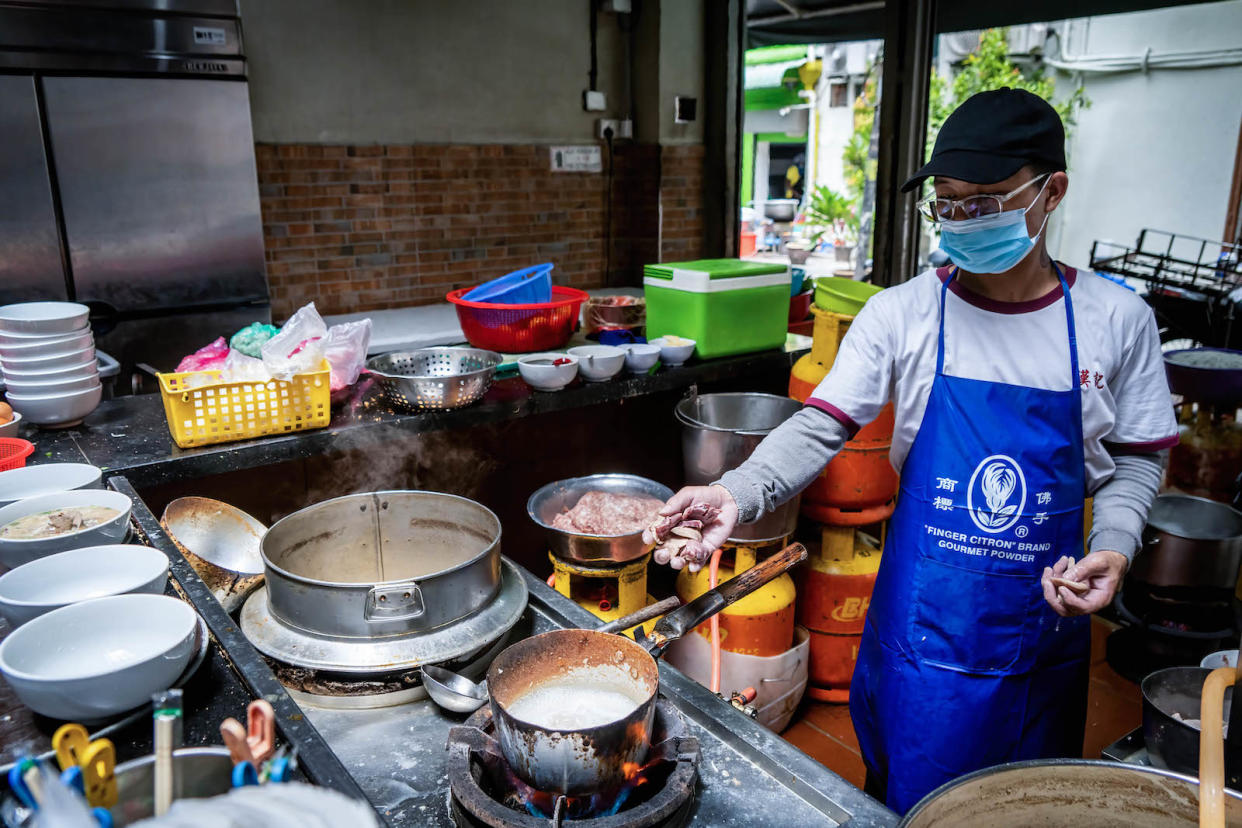 A hawker making fresh noodles in Penang, illustrating conversations on food and cost of living.