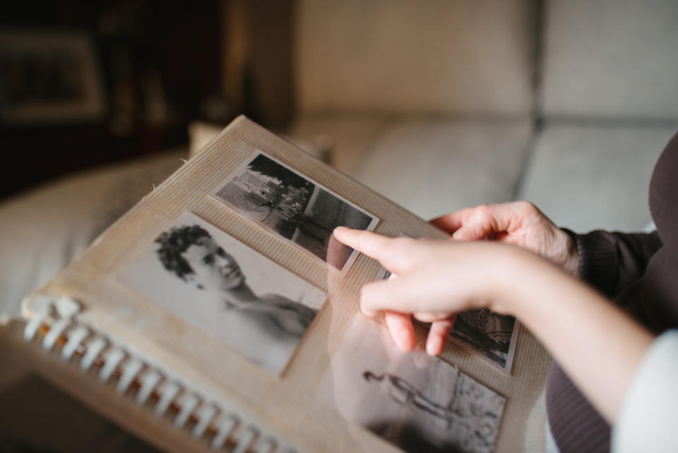 Person's hands turning pages of an old photo album with black-and-white pictures