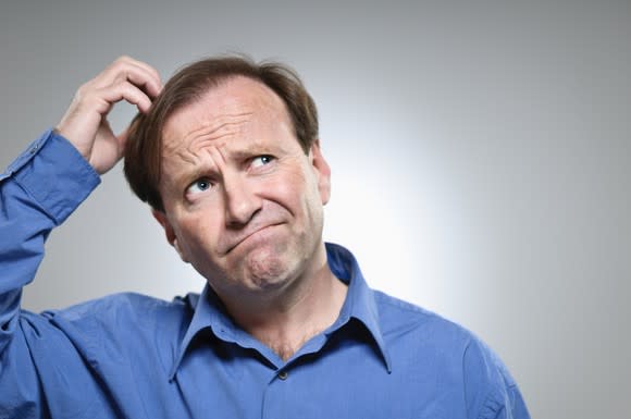 A confused man scratching the top of his head.